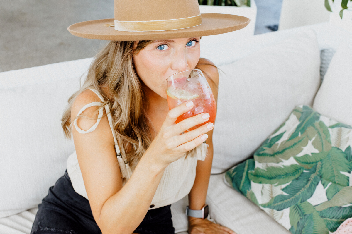 Ragazza con cappello che beve uno Spritz, uno dei cocktail meno calorici.