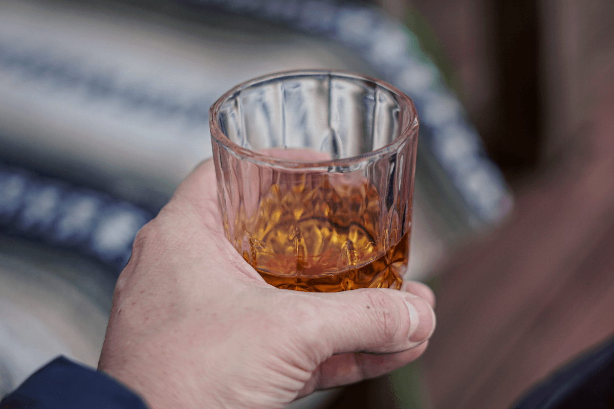 Uomo con in mano un bicchiere di Bourbon whiskey